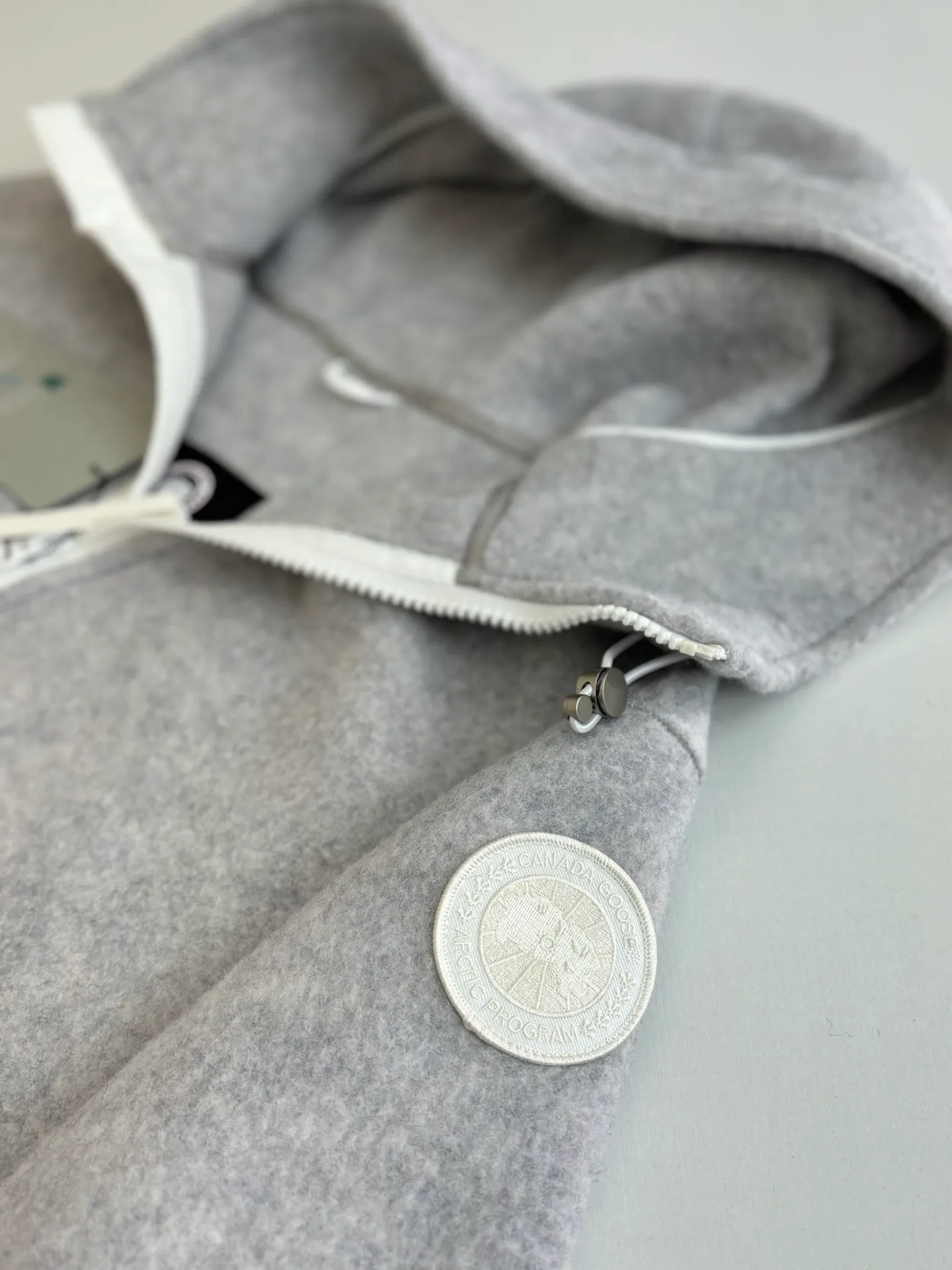 P810 Canada Goos*/Big Goose Fleece Badge Hooded Jacket The fabric is made of wool as the main body, with a very small amount of spandex and polyester fiber blended into the wool fleece fabric. The sleeves and hem are closed with 2×2 ribbing. Its strong elasticity can closely fit wrists and waists of different thicknesses, forming an effective 'seal' to prevent cold wind from blowing back. It can still maintain its original shape after repeated stretching and use, and is not easy to loose and deform. And the ribbed cuffs can convey a sense of design and enhance the visual beauty.  Size：S/M/L/XL